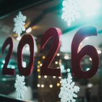 Foto von Christian Agbede auf Unsplash. (Für Alt-Text: Red 2026 numbers with snowflakes on window)