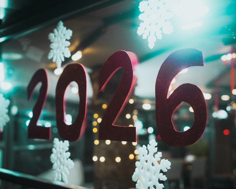 Foto von Christian Agbede auf Unsplash. (Für Alt-Text: Red 2026 numbers with snowflakes on window)